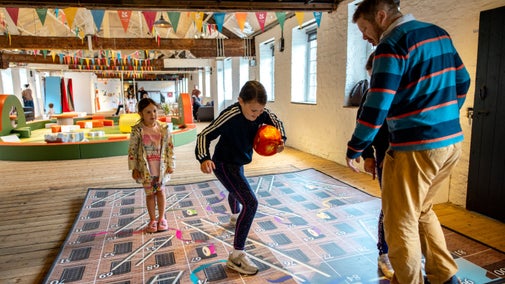 An adult and 3 children stood on a giant board game